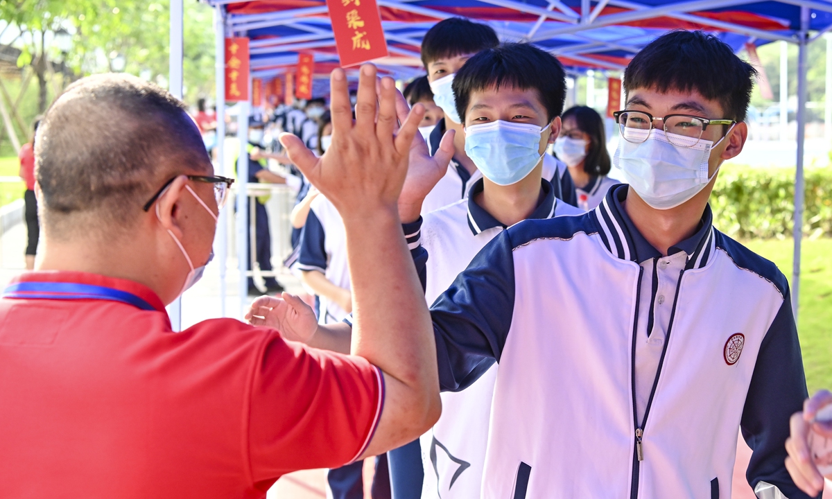 A teacher gives a high five to a student outside an examination point at a high school in Guangzhou, South China's Guangdong Province. A total of 10.78 million Chinese students across the country stepped into Gaokao examination rooms on Monday to take their final step toward college. Photo: VCG