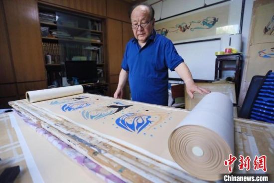 图为范兴儒展示他最珍视的《八十七飞天卷》，耗时5年所作，画卷长50米，包含87身代表飞天。　高展 摄